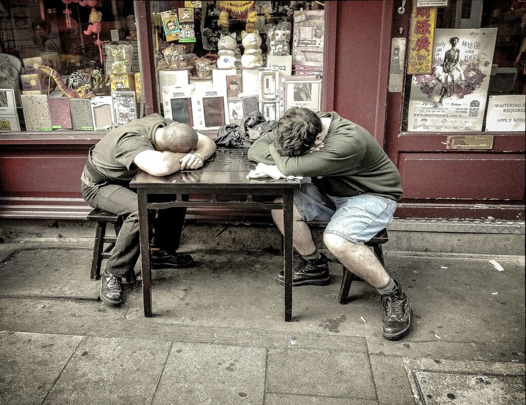 Zwei Männer entspannen schlafend vor einem Laden - Schlafwissenschaft neu erkunden!